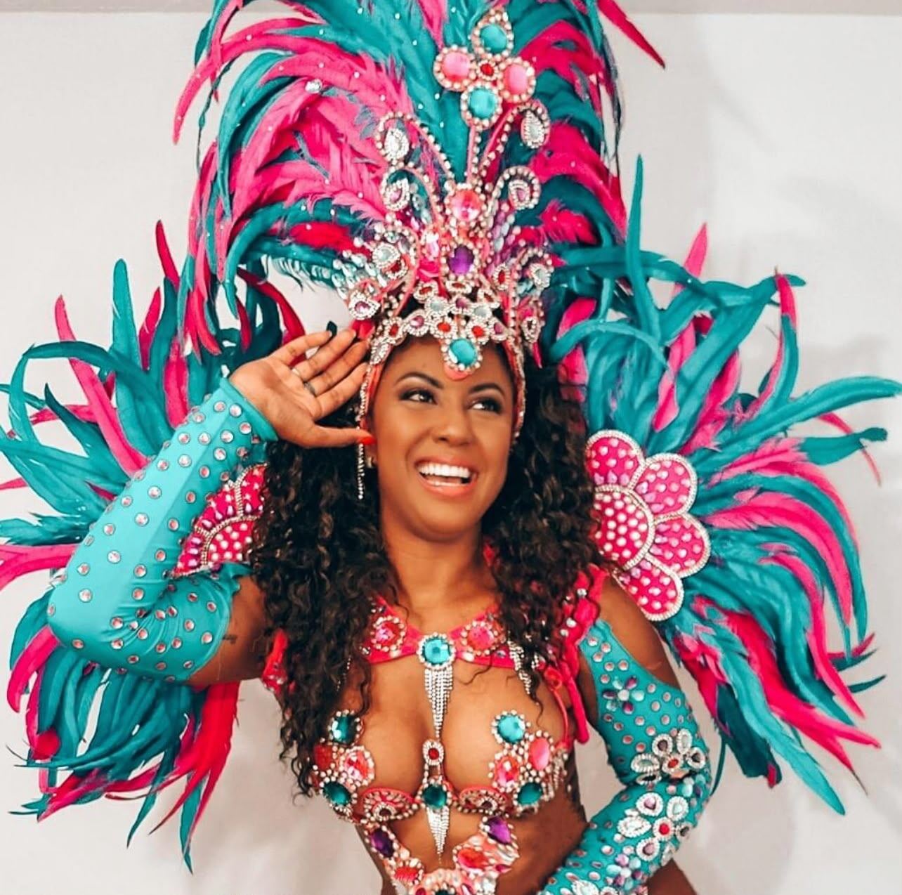 Andressa Telles, founder and CEO of Royalty Samba, smiling in a pink and turquoise Carnival costume