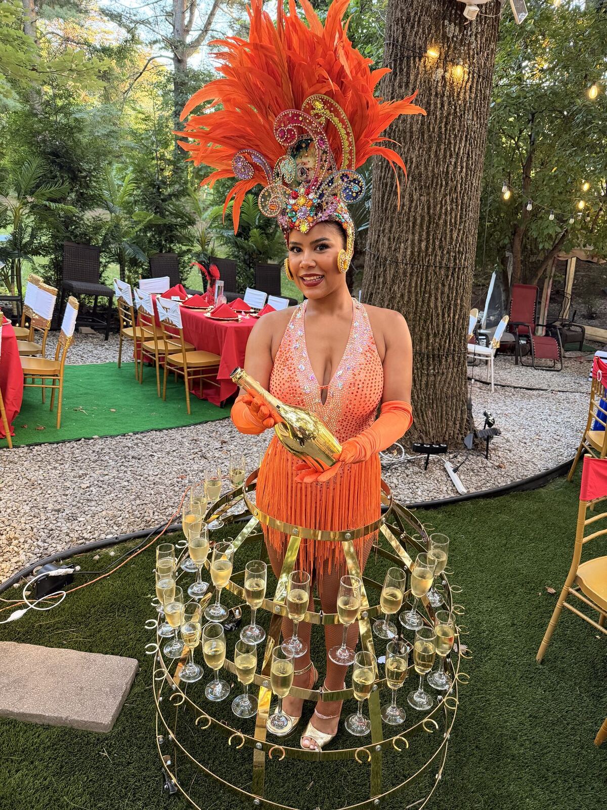 Royalty Samba performer serving champagne in an orange Carnival costume